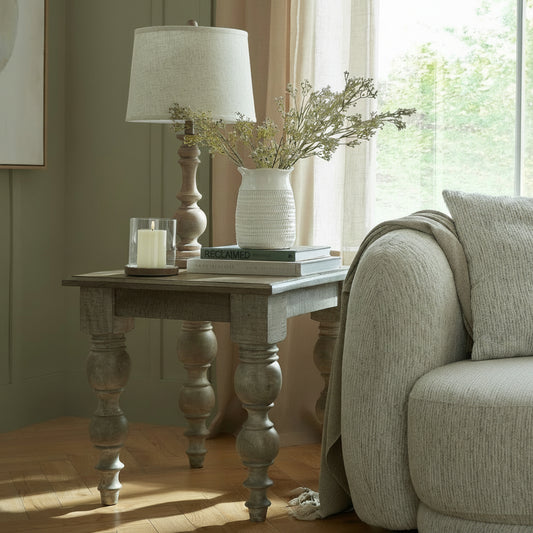 Living room with a wooden side table, lamp, and books near a sofa.
