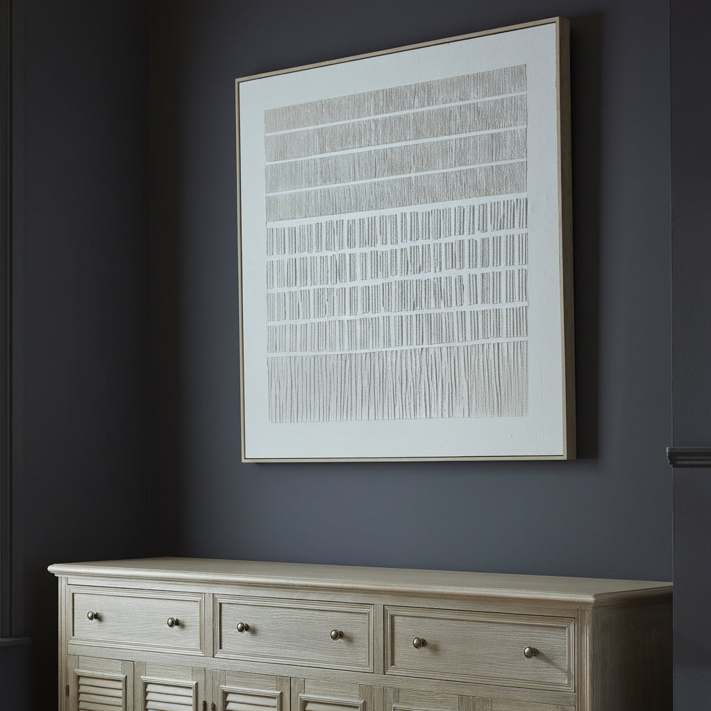 Decorative setting with a lamp, vase of flowers, and framed artwork on a wooden dresser.