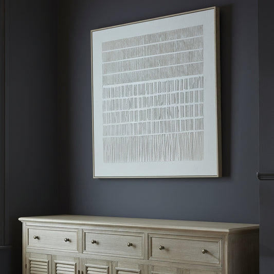 Decorative setting with a lamp, vase of flowers, and framed artwork on a wooden dresser.