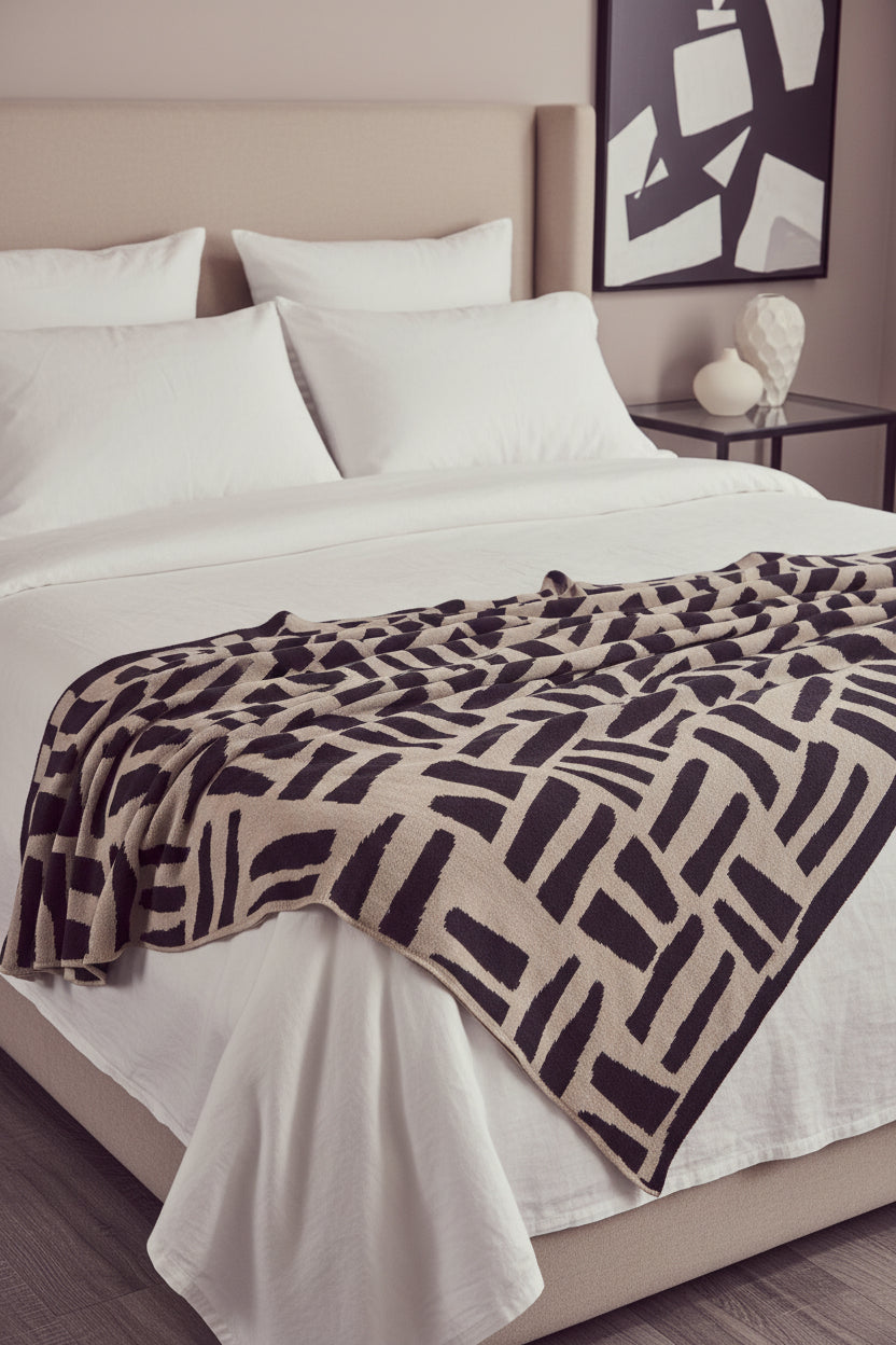 Patterned blanket draped over a dark leather sofa in a living room setting.