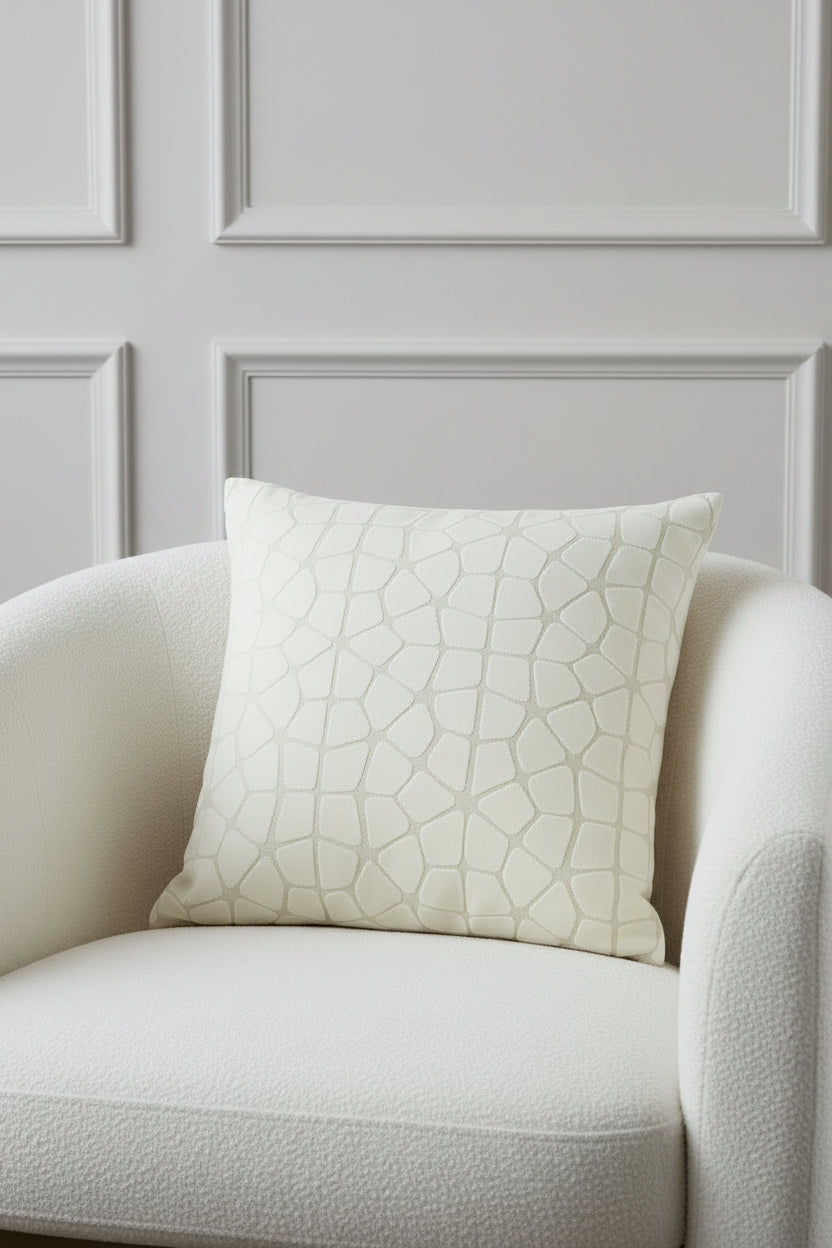 A square throw pillow featuring a textured, raised geometric pattern resembling a stone or reptile skin motif in a light beige and off-white color palette, shown against a plain white background.
