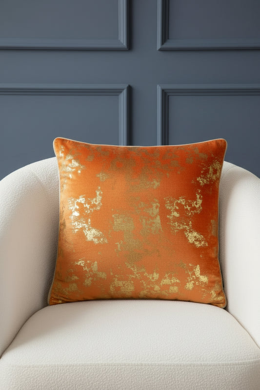 Orange pillow with gold metallic accents on a white background