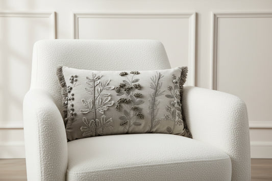 Decorative pillow with floral embroidery and tassels on a white background