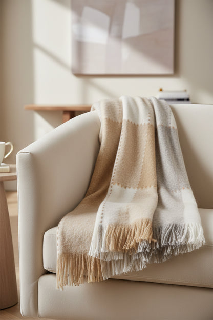 Folded beige and white blanket with frayed edges on a white background
